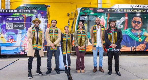 Artists pose in front of wrapped street cars