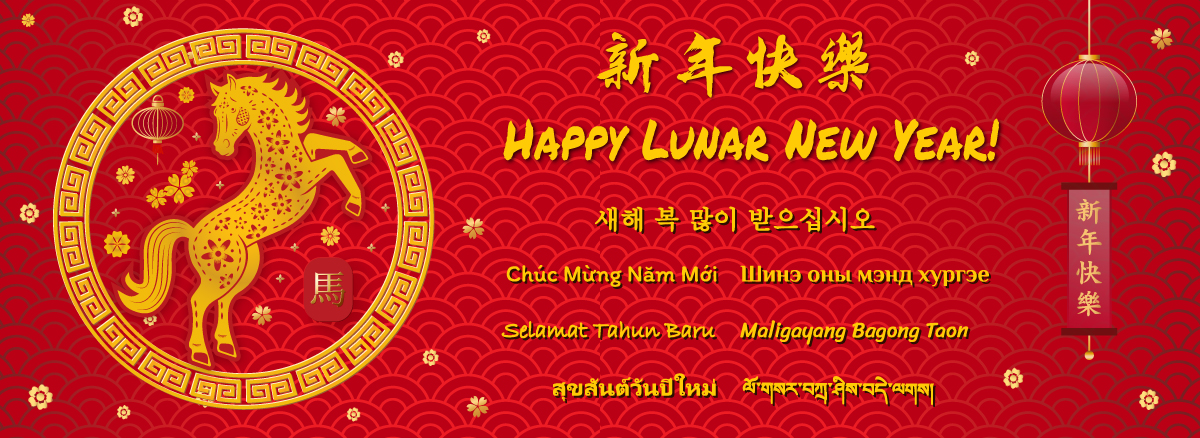 A red and gold Lunar New Year greeting graphic featuring a decorative circular emblem with a stylized golden horse surrounded by lanterns and floral patterns. To the right, the text ‘Happy Lunar New Year!’ appears in English and multiple other languages, including Chinese, Korean, Vietnamese, Mongolian, Malay, Filipino, Thai, and Tibetan. A red lantern with a vertical banner displaying Chinese characters hangs on the right side. The background is patterned with traditional wave motifs and small floral elements.