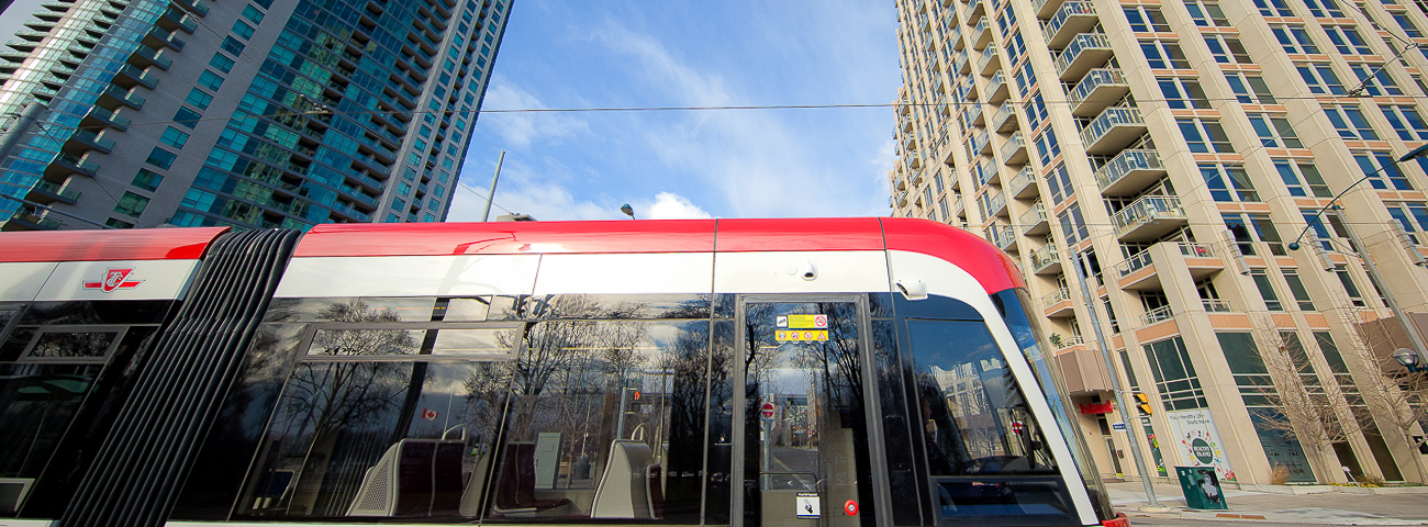 Image of the front end of a new streetcar with high rise buildings in the rear