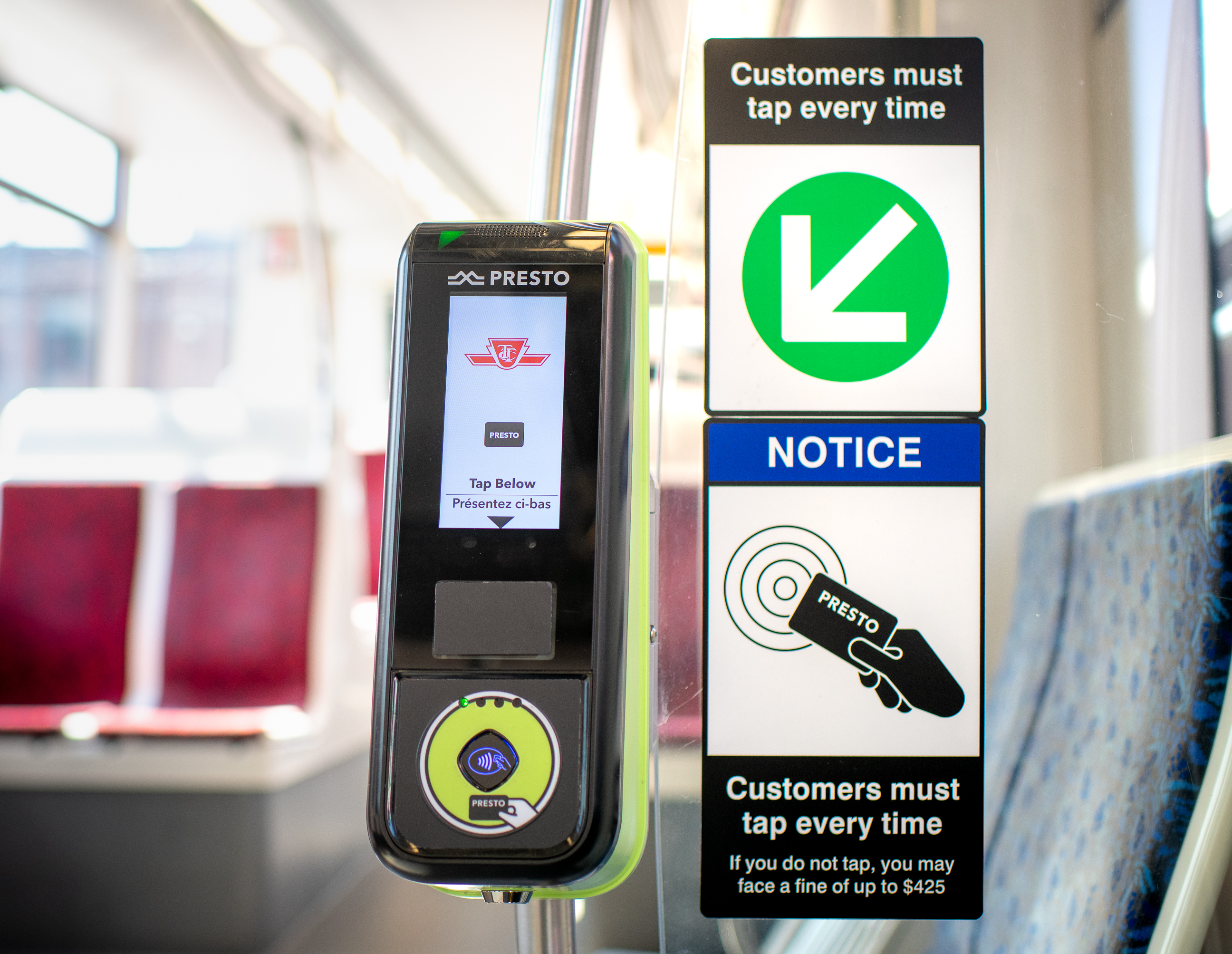 A black PRESTO Reader on a TTC streetcar next to a sign with the text "Customers must tap every time"