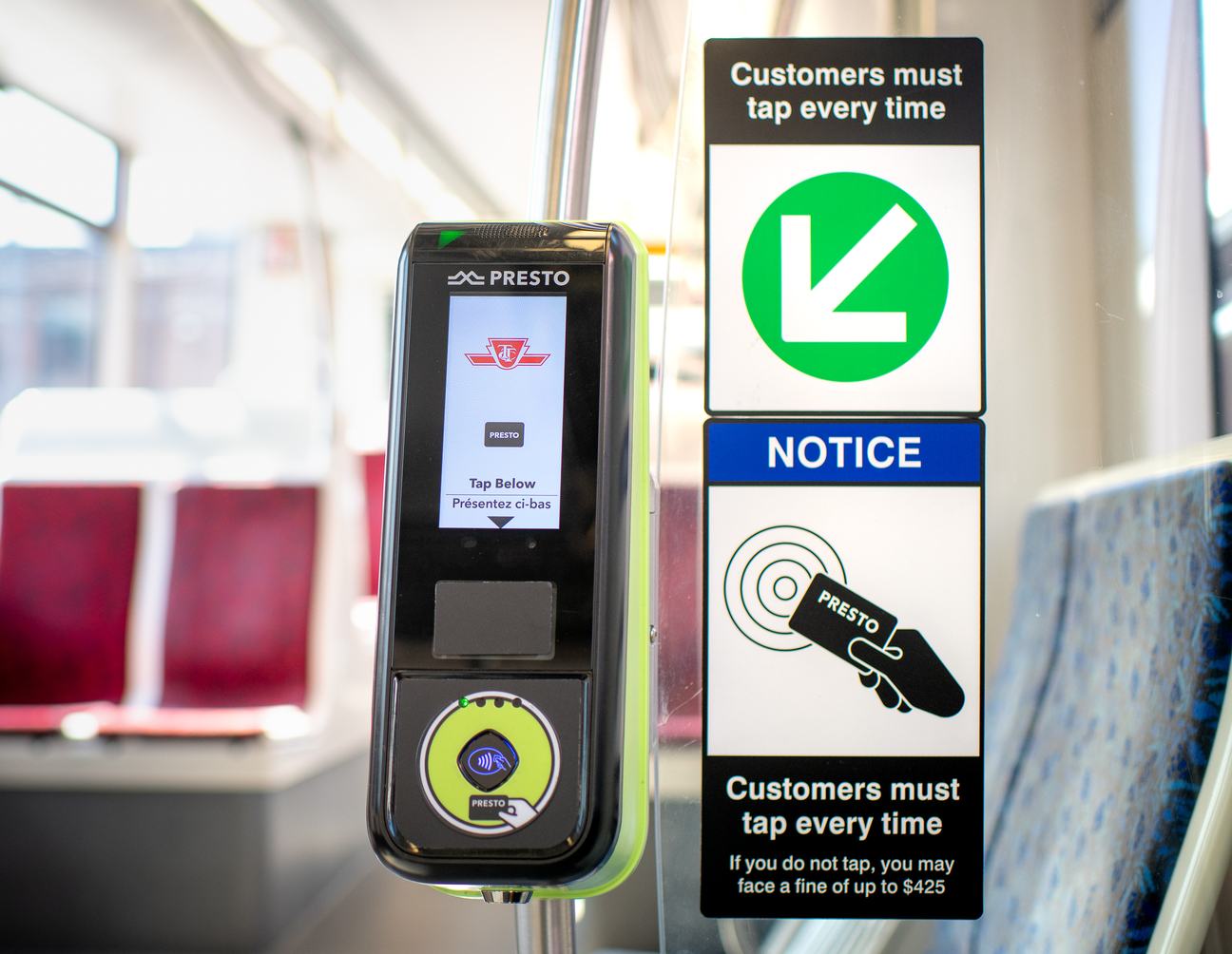 – A PRESTO reader on a streetcar beside notices about proof-of-payment and a green arrow showing customers where to tap