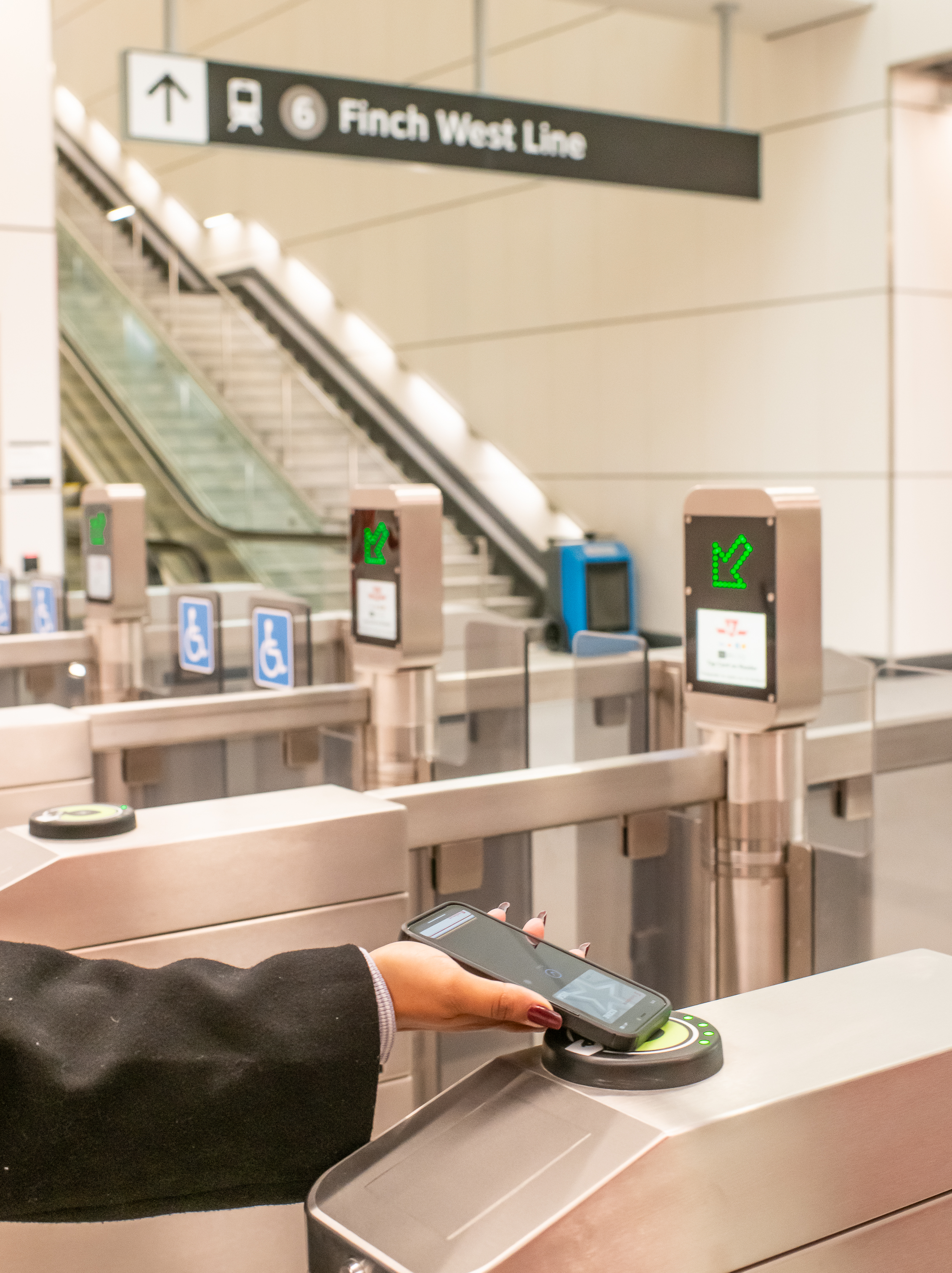 A person’s hand tapping a mobile device on a PRESTO reader at a fare gate