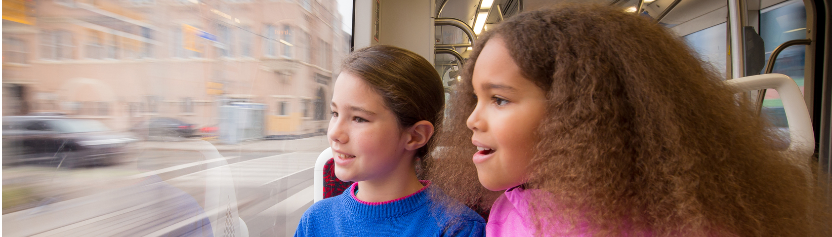 Children looking out a streetcar window while the city blurs by