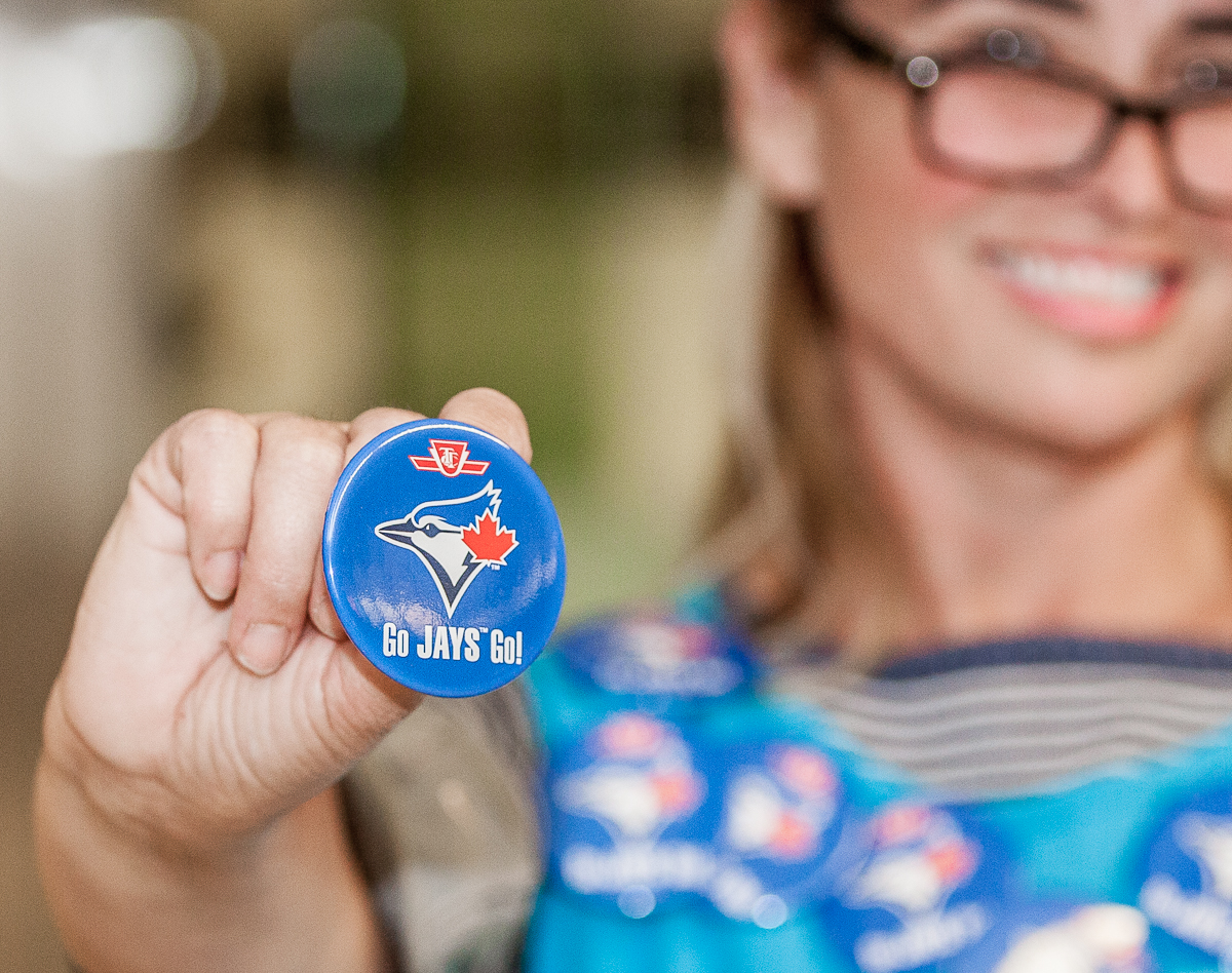 A lady holding a TTC branded 'Go Jays Go' badge.