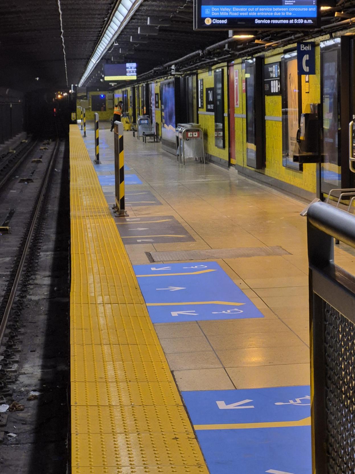 Metal platform edge barriers on the TMU Station subway platform installed beside the yellow line.