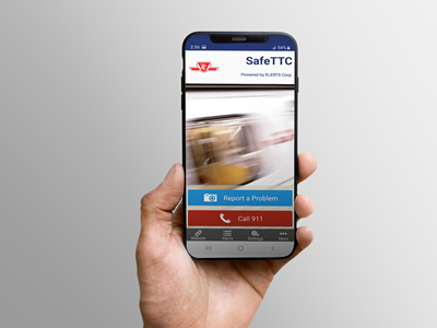 Hand holding a phone showing SafeTTC app on screen.