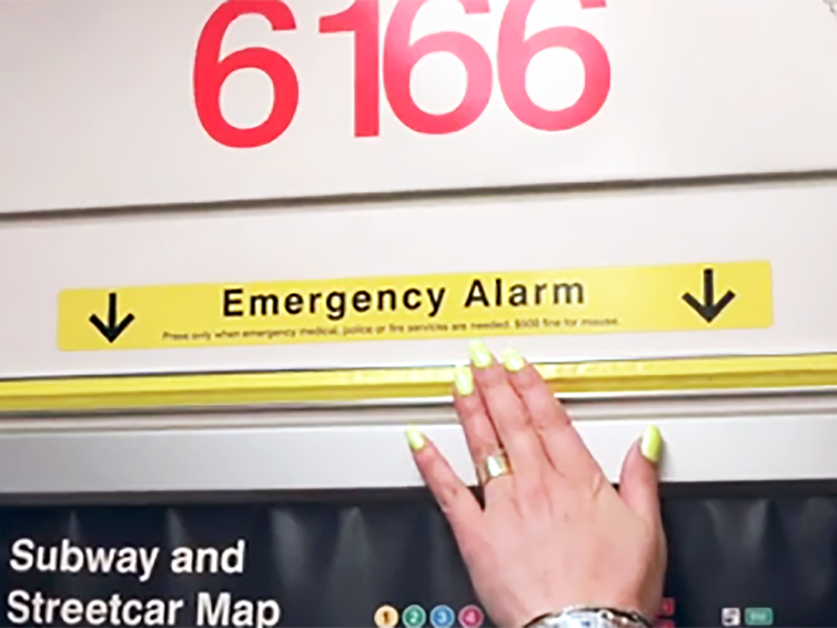 Hand pressing Emergency Alarm strip on subway