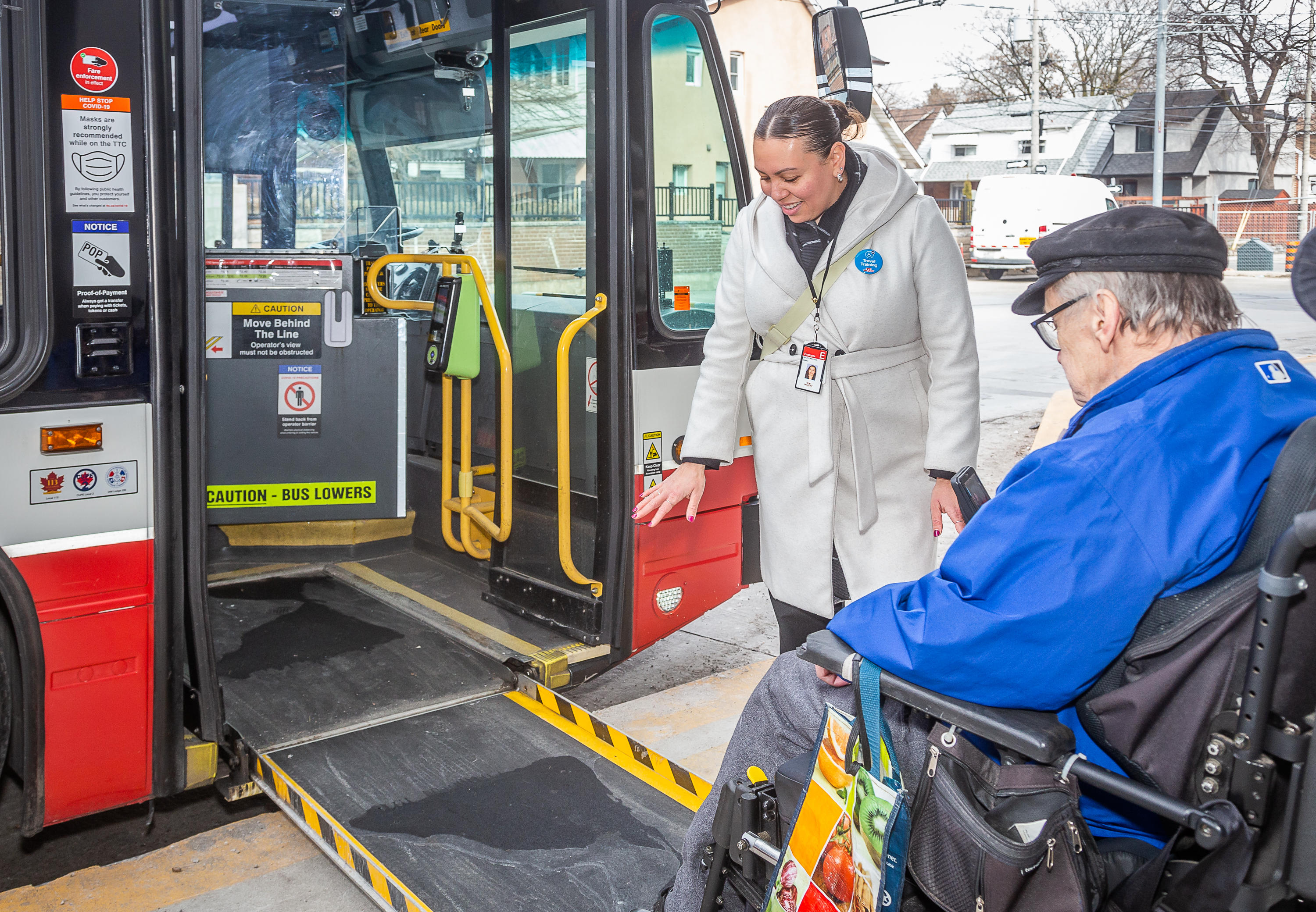 A TTC Travel Trainer guides a customer using a wheelchair as they enter a TTC bus