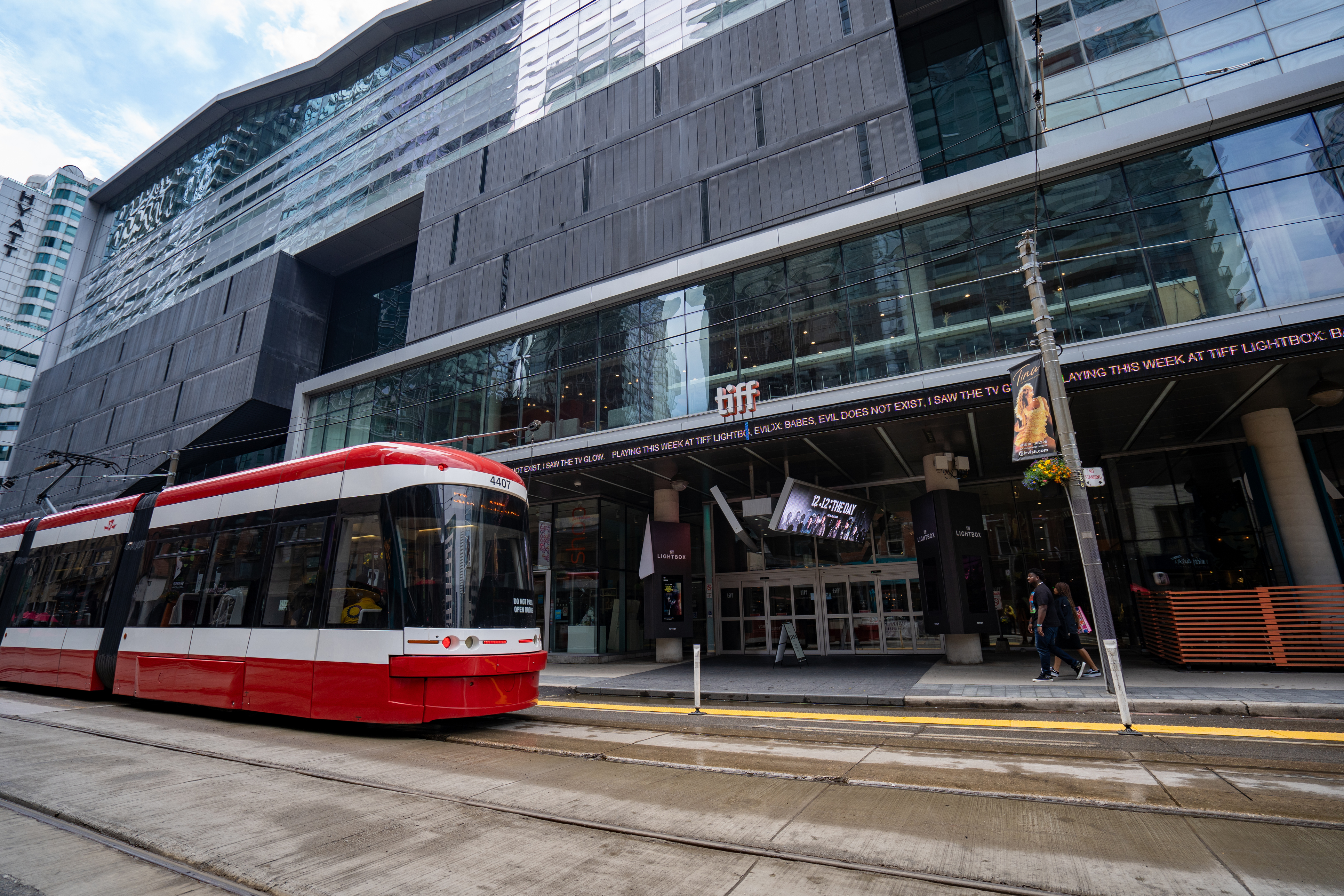 A red and white TTC streetcar passing by a TIFF building in downtown Toronto.