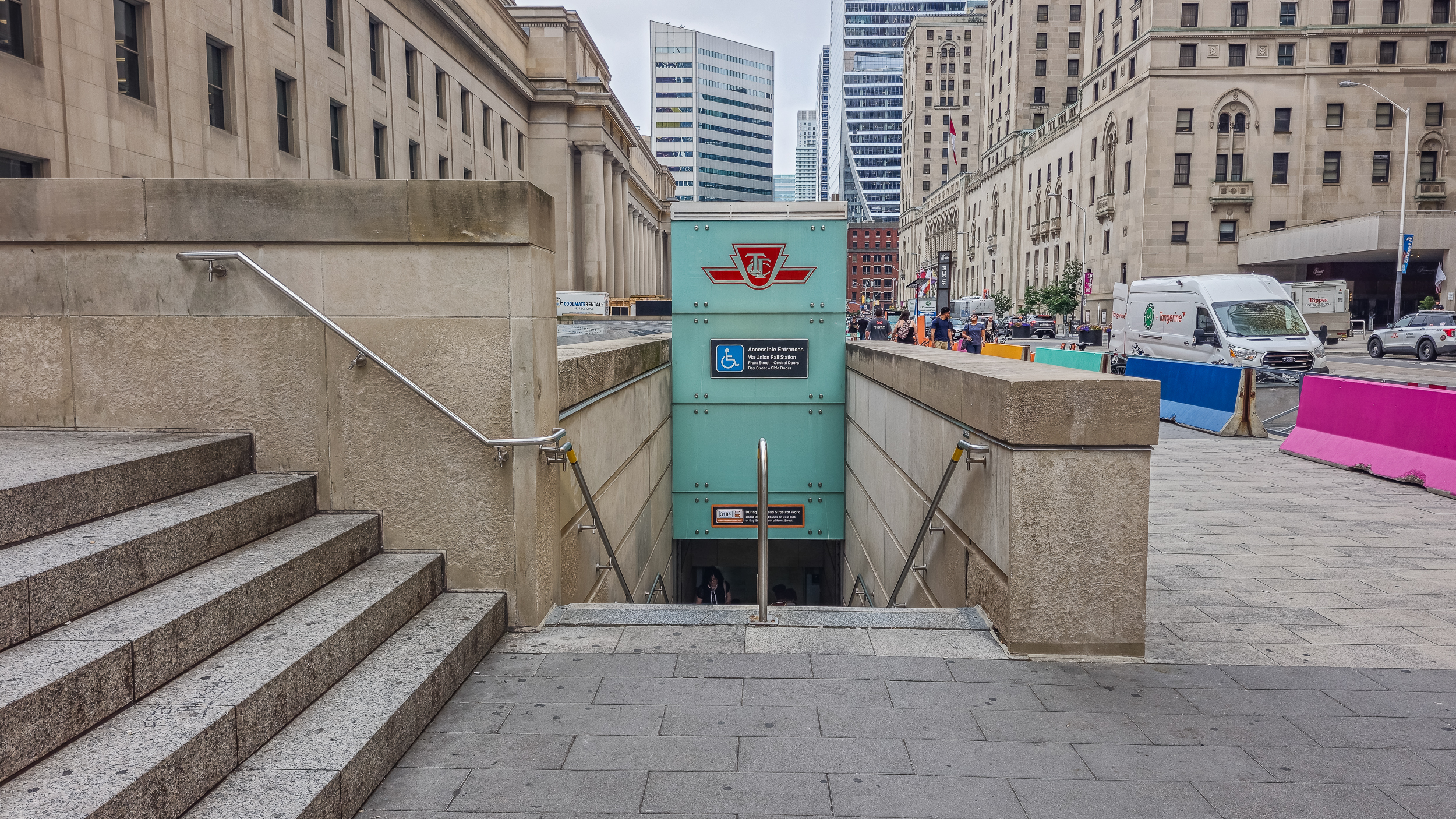 Modern-day view of a stairwell entrance to TTC’s Union Station subway, with city buildings and street traffic in the background. 