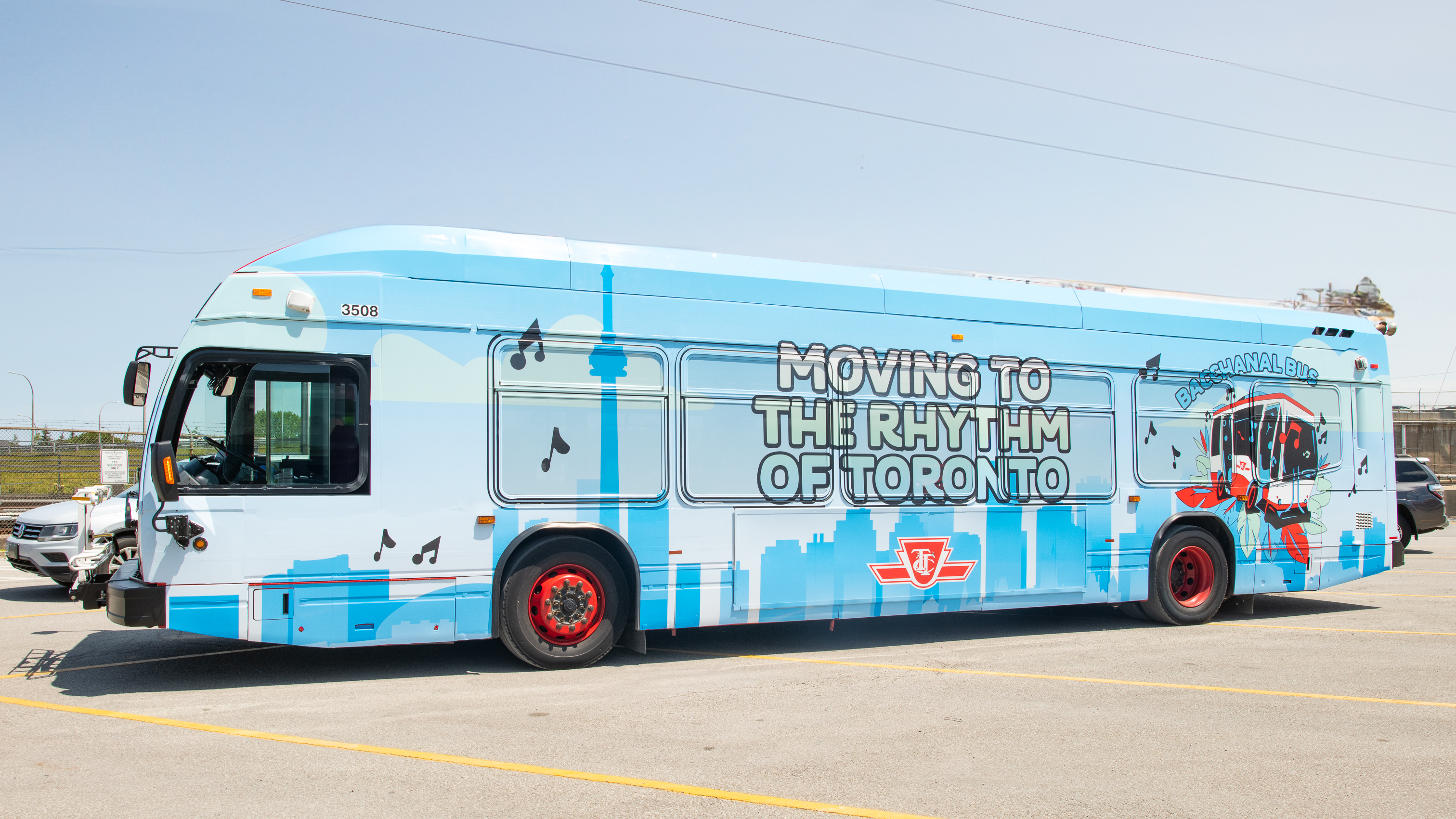 TTC bus with a blue and white Toronto skyline wrap and the text "Moving to the Rhythm of Toronto" and "Bacchanal Bus".