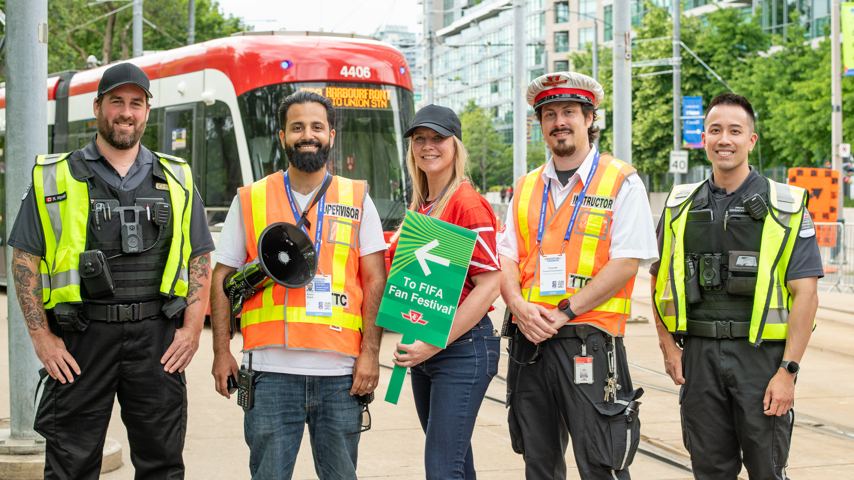 TTC employees from various departments posing in front of a TTC Harbourfront streetcar.