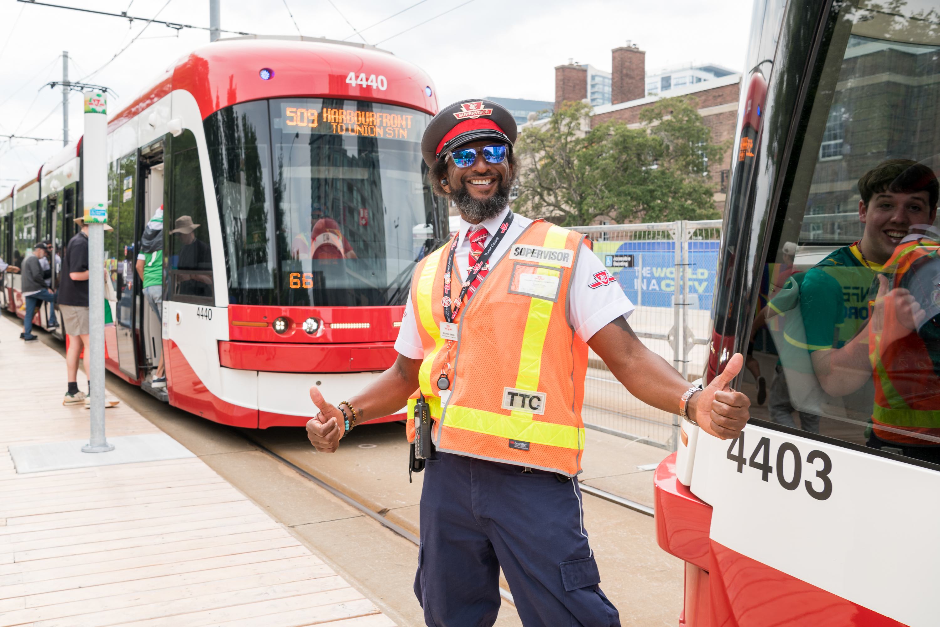 TTC Operator posing, giving two thumbs up standing beside a 509 Harbourfront streetcar