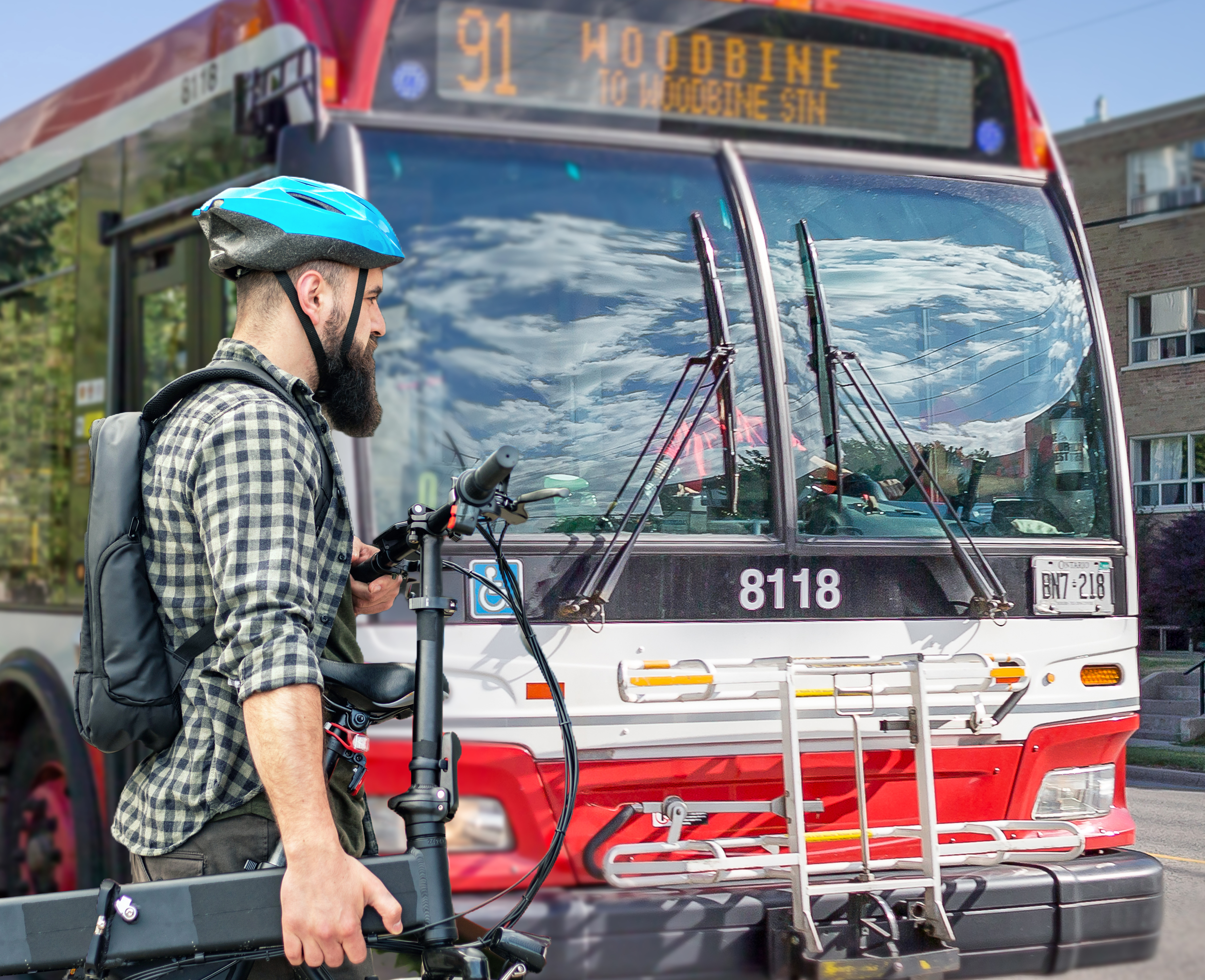 A person wearing a helmet and holding a bicycle standing in front of a 91 Woodbine TTC bus.