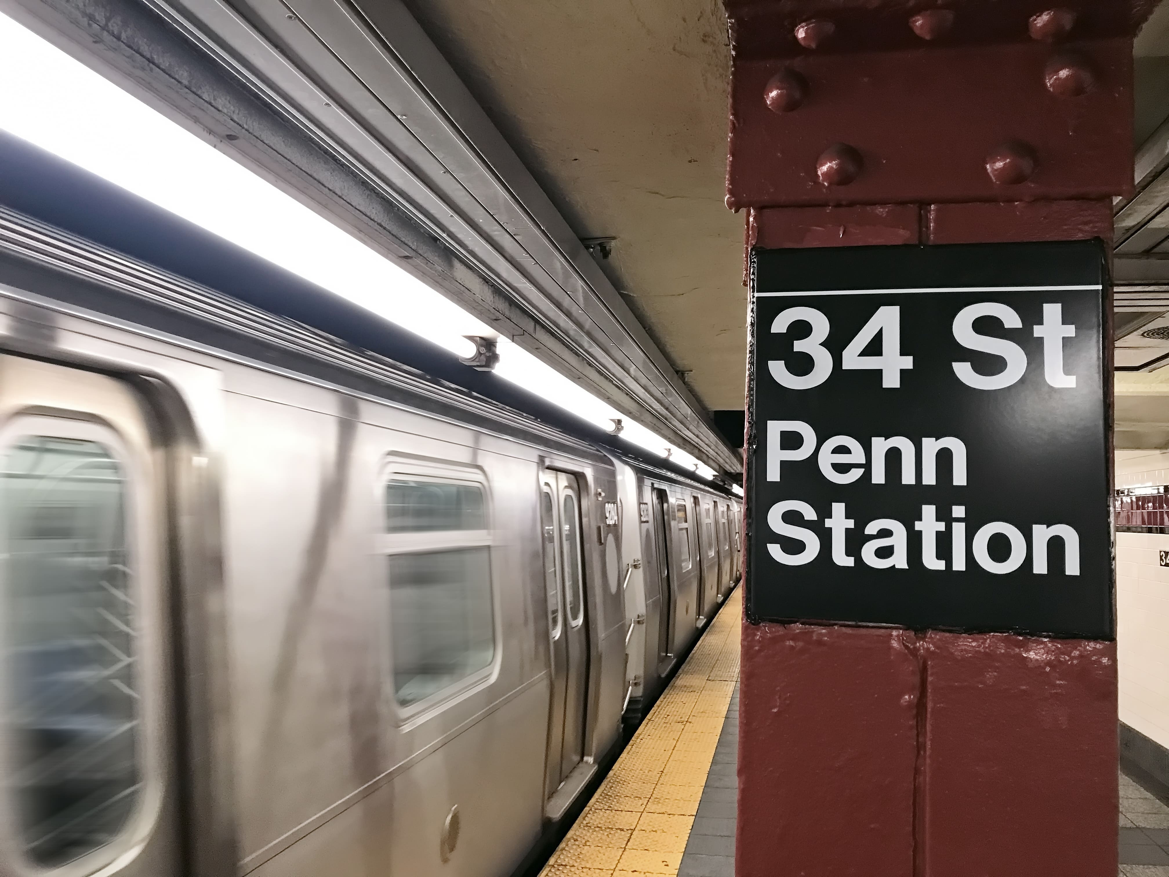A subway train departing the platform of New York's 34th Street Penn Station stop.