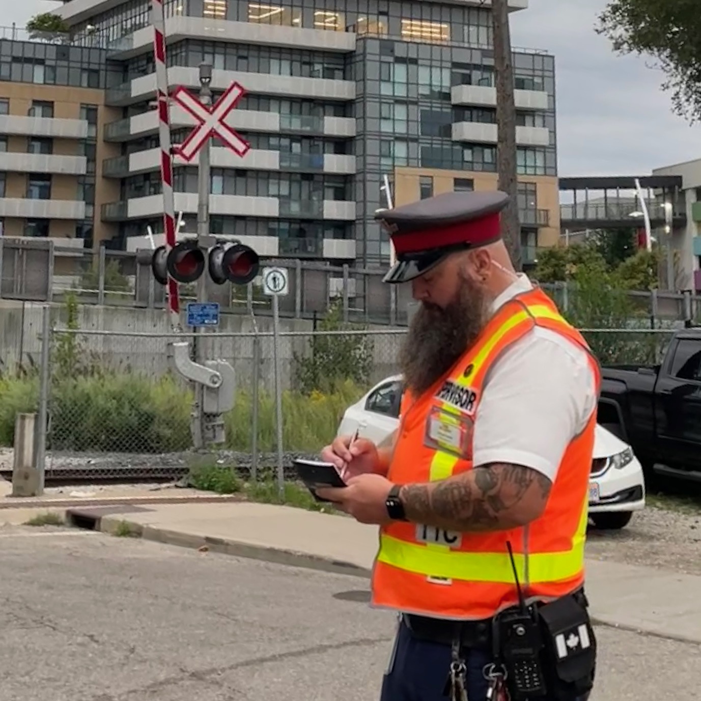 A TTC Mobile Supervisor wearing an orange and yellow safety vest and writing in a notebook.