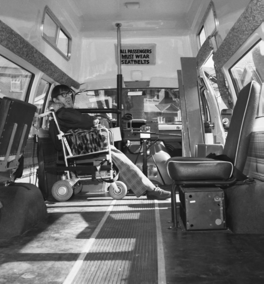 A Wheel-Trans passenger who uses a wheelchair is seating inside a Wheel-Trans bus.