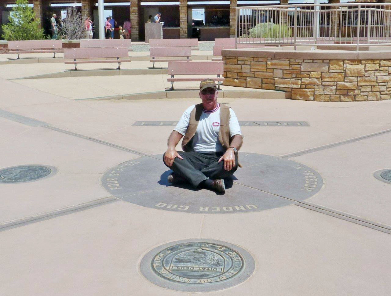 In the desert at the Four Corners, the only place in the U.S. where four states meet at one point. I am sitting facing Arizona. It was 102 degrees F that day! Photo courtesy Gord Friedrich, pensioner