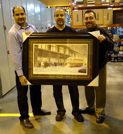 Recipient: Senior Storeperson Sandro Creazzo, centre, received his 25-year print. Location: Malvern Garage Stores. Presenters: Area Supervisor John Locantore, left, and Distributed Inventory Control Manager Mike Le Pera, right.